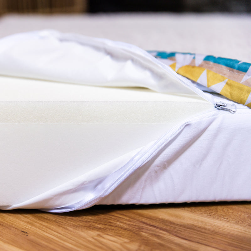 A close-up of the Replacement Waterproof Liner for Memory Foam Dog Bed, shown inside a white zippered mattress cover that&